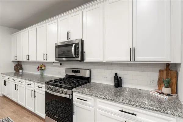 a large kitchen with granite countertop lots of counter space and stainless steel appliances