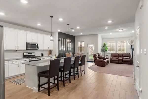 a kitchen with stainless steel appliances granite countertop a sink a stove a dining table and chairs