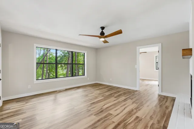 a view of an empty room with wooden floor fireplace and a window