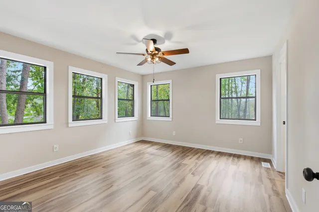 a view of an empty room with wooden floor and a window