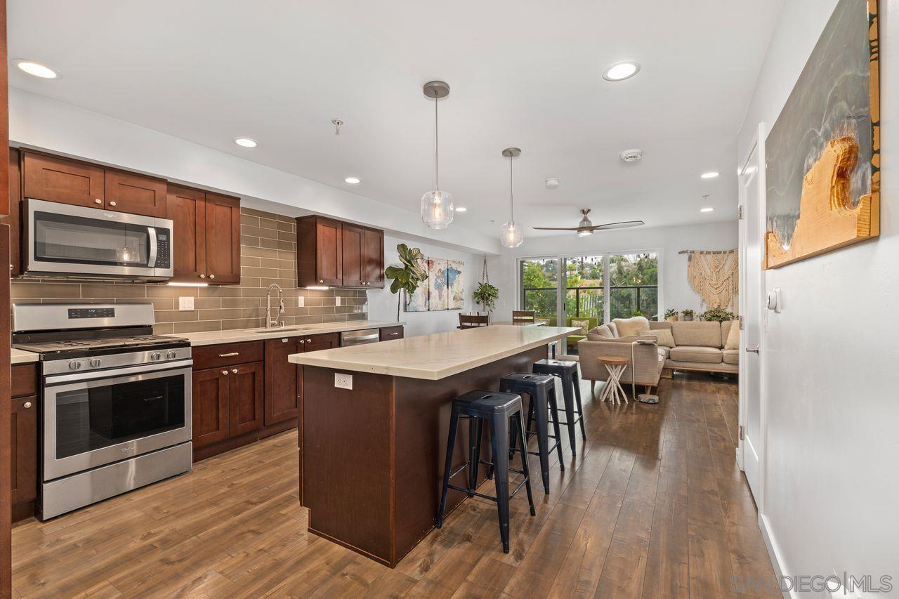 4100 Voltaire Street, Unit 210 San Diego, CA 92107 - Photo 1 of 35 a kitchen with stainless steel appliances granite countertop a stove top oven a sink dishwasher a dining table and chairs with wooden floor