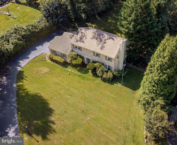an aerial view of a house with swimming pool and large trees