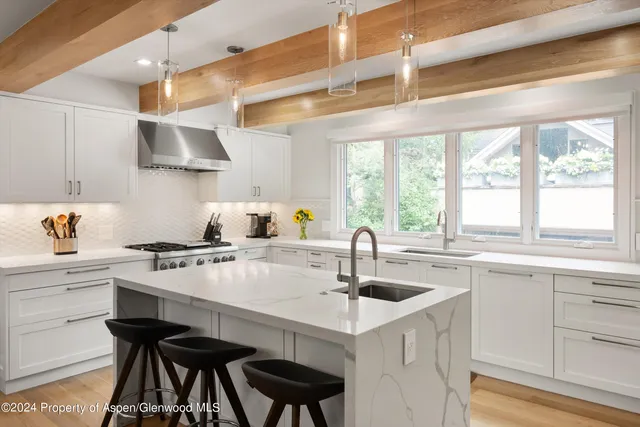 a kitchen with stainless steel appliances a sink a stove and white cabinets next to a window