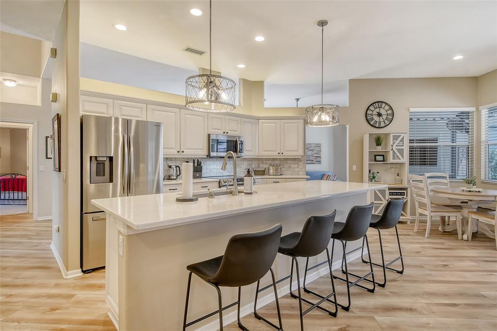 6738 Pleasant Hill Road Bradenton, FL 34203 - Photo 15 of 93 a large kitchen with stainless steel appliances kitchen island granite countertop a table chairs and a refrigerator
