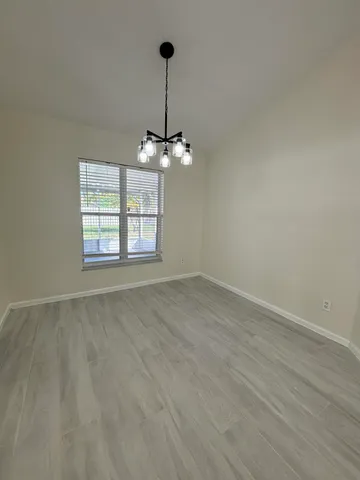 a view of an empty room with window and chandelier fan