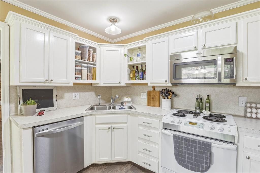 110 Peggy Ruth Drive Longview, TX 75605 - Photo 11 of 27 Bright kitchen featuring extensive white cabinetry, a double basin stainless steel sink, stainless steel dishwasher, stainless steel over-the-range microwave, and a white electric range with a ceramic cooktop