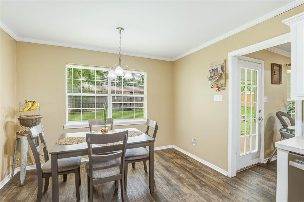 110 Peggy Ruth Drive Longview, TX 75605 - Photo 12 of 27 Dining area featuring wood-finish flooring, a window overlooking the backyard, crown molding, a multi-light pendant fixture, and a French door with multiple lites