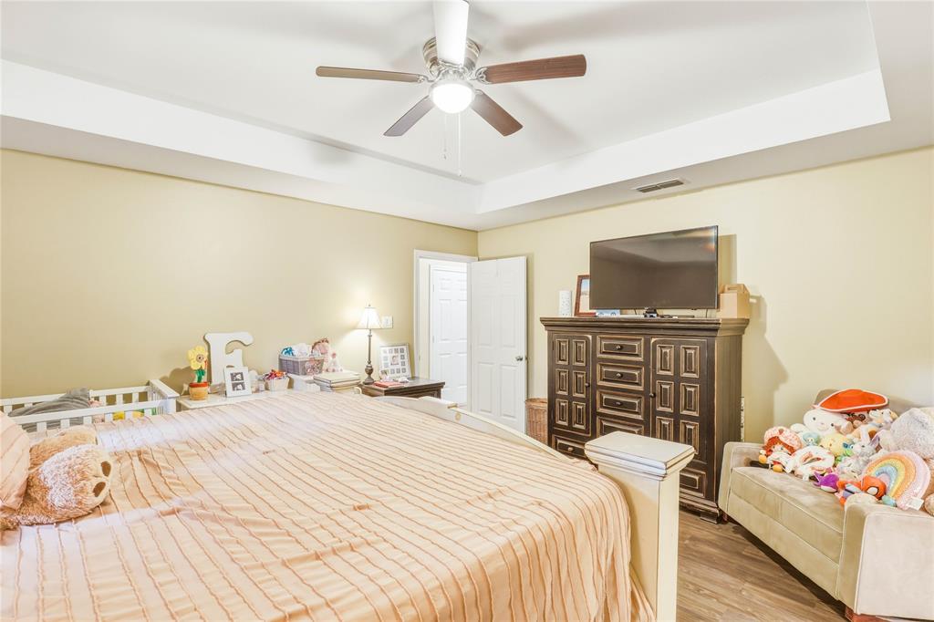 110 Peggy Ruth Drive Longview, TX 75605 - Photo 15 of 27 Spacious bedroom featuring a tray ceiling, ceiling fan with light fixture, light neutral wall paint, and wood-finish flooring
