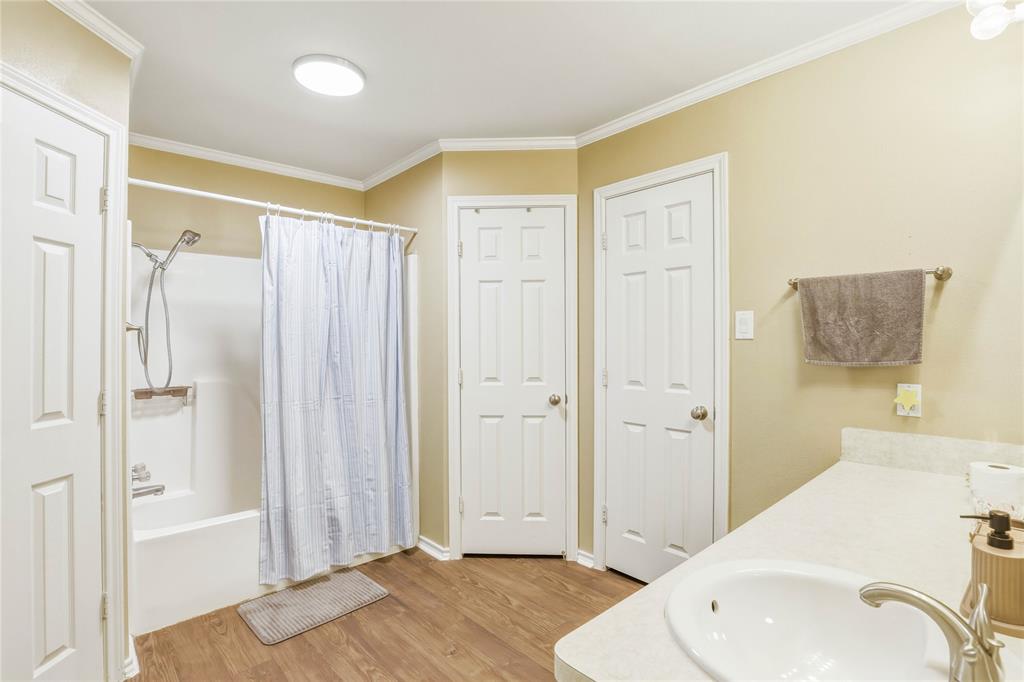 110 Peggy Ruth Drive Longview, TX 75605 - Photo 16 of 27 Bathroom featuring a tub/shower combination with a built-in shelf, wood-finish flooring, a single vanity with an integrated sink, and crown molding