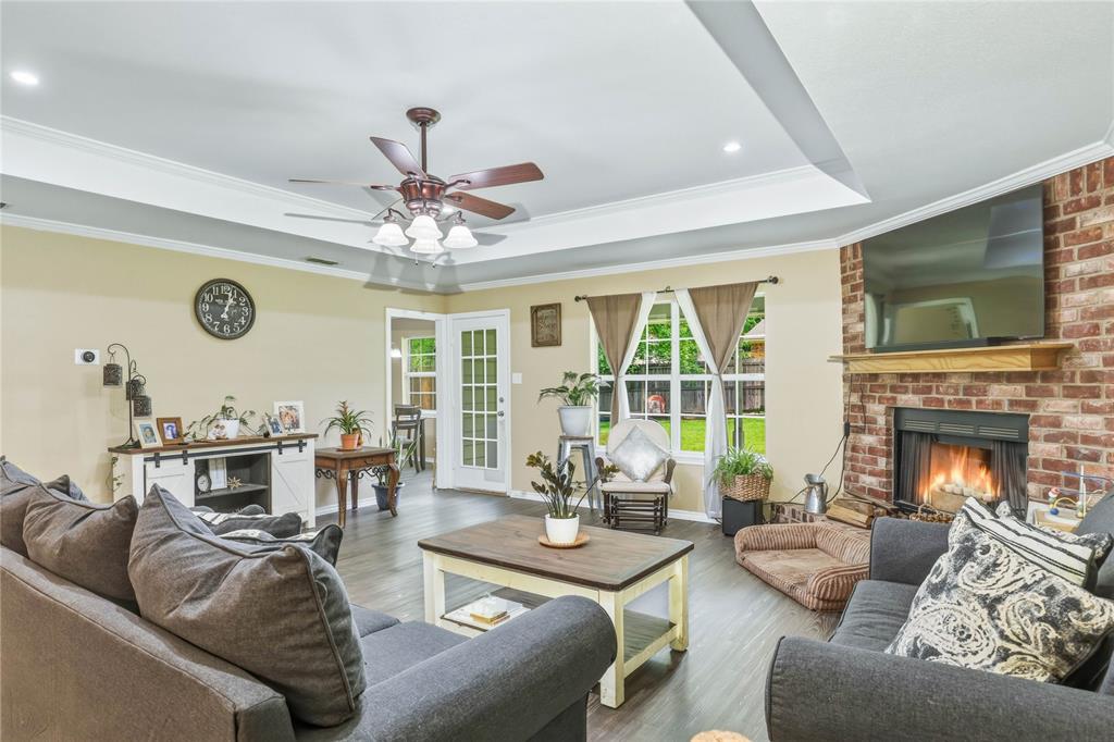 110 Peggy Ruth Drive Longview, TX 75605 - Photo 6 of 27 Living area featuring a brick fireplace with a wood mantle, tray ceiling, and wood-finish flooring