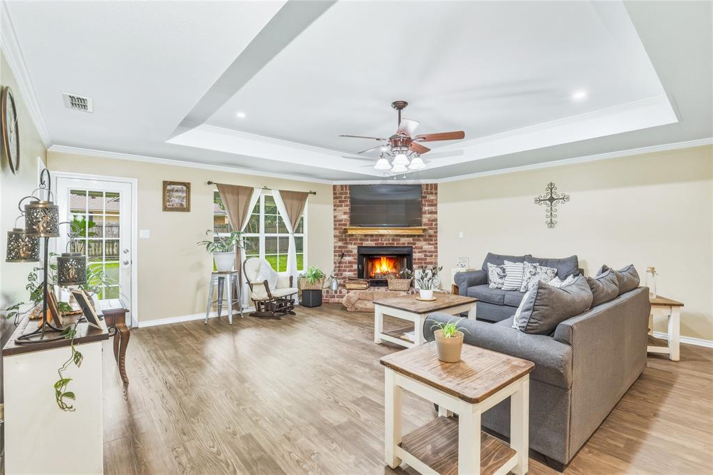 110 Peggy Ruth Drive Longview, TX 75605 - Photo 7 of 27 Living room featuring wood-finish flooring, a tray ceiling with a ceiling fan, and a brick fireplace with a wood mantel