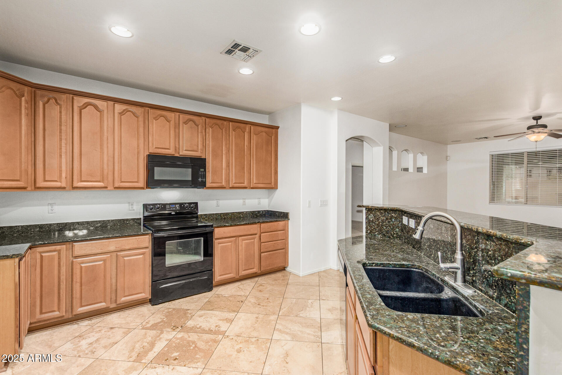 9228 West Black Hill Road Peoria, AZ 85383 - Photo 13 of 44 a kitchen with granite countertop a stove sink and cabinets