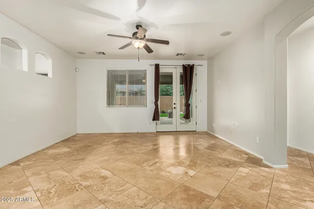 a view of an empty room with chandelier fan and windows