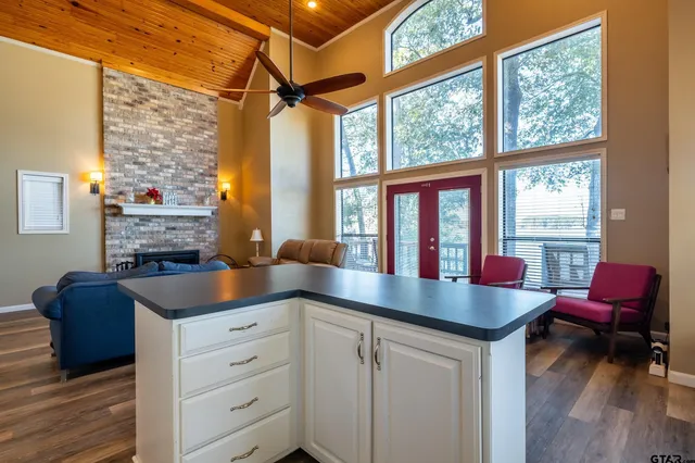 a kitchen with kitchen island a stove a refrigerator a sink and a dining table with wooden floor