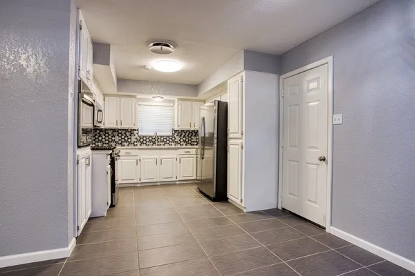 a kitchen with a refrigerator and white cabinets