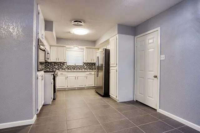 a kitchen with a refrigerator and white cabinets