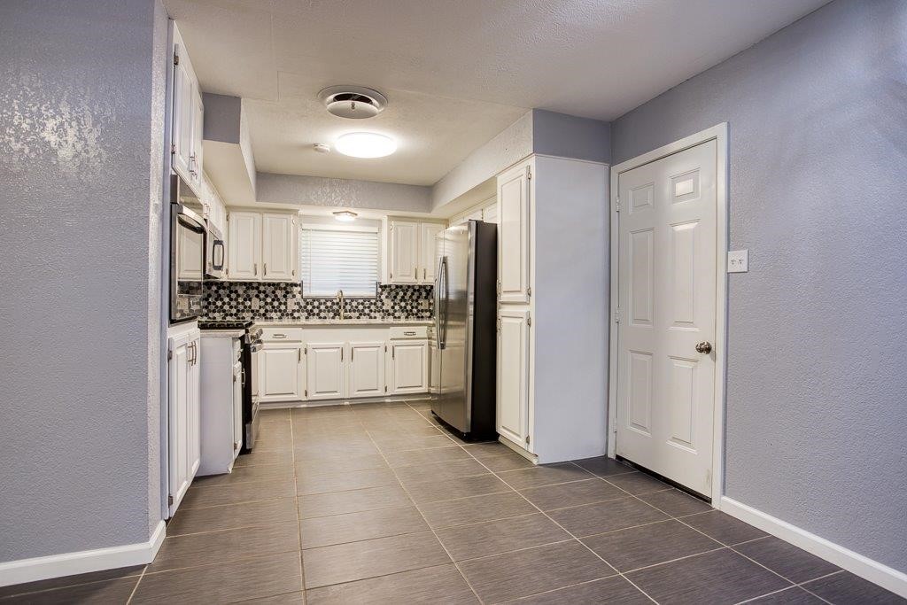 10733 Timbergrove Lane Corpus Christi, TX 78410 - Photo 11 of 40 a kitchen with a refrigerator and white cabinets
