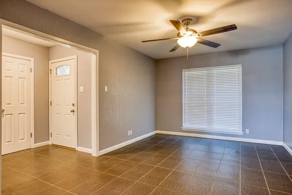a view of an empty room with a ceiling fan and window