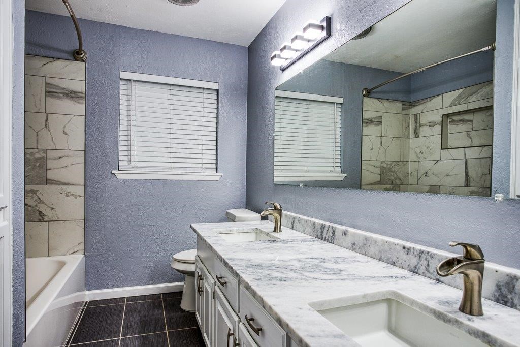 10733 Timbergrove Lane Corpus Christi, TX 78410 - Photo 26 of 40 a bathroom with a granite countertop sink a mirror and a shower