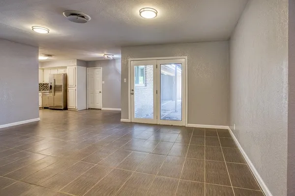 a view of an empty room with glass door and chandelier fan