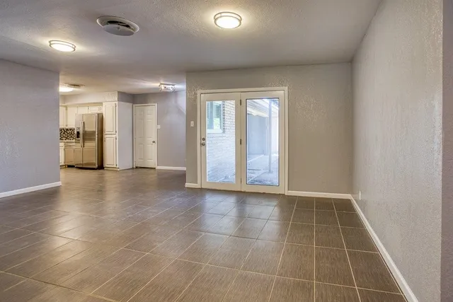 a view of an empty room with glass door and chandelier fan