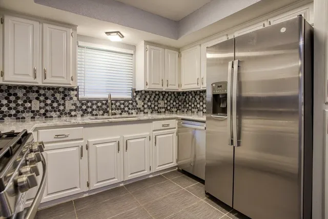 a kitchen with white cabinets sink and refrigerator