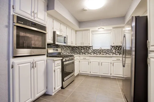 a kitchen with granite countertop white cabinets and stainless steel appliances