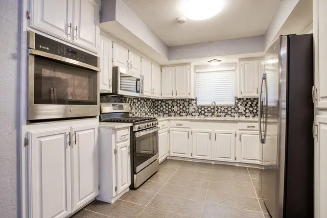 a kitchen with granite countertop white cabinets and stainless steel appliances