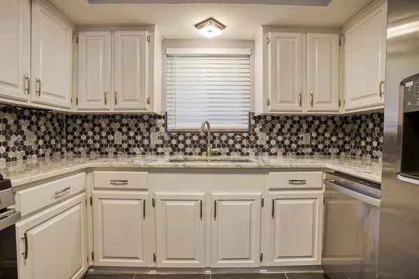 a kitchen with white cabinets and sink