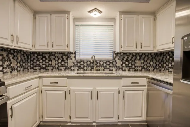 a kitchen with white cabinets and sink