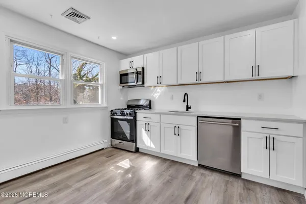 a kitchen with white cabinets a sink a window and appliances