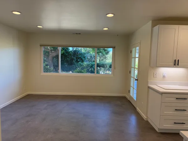 an empty room with a window and a kitchen view