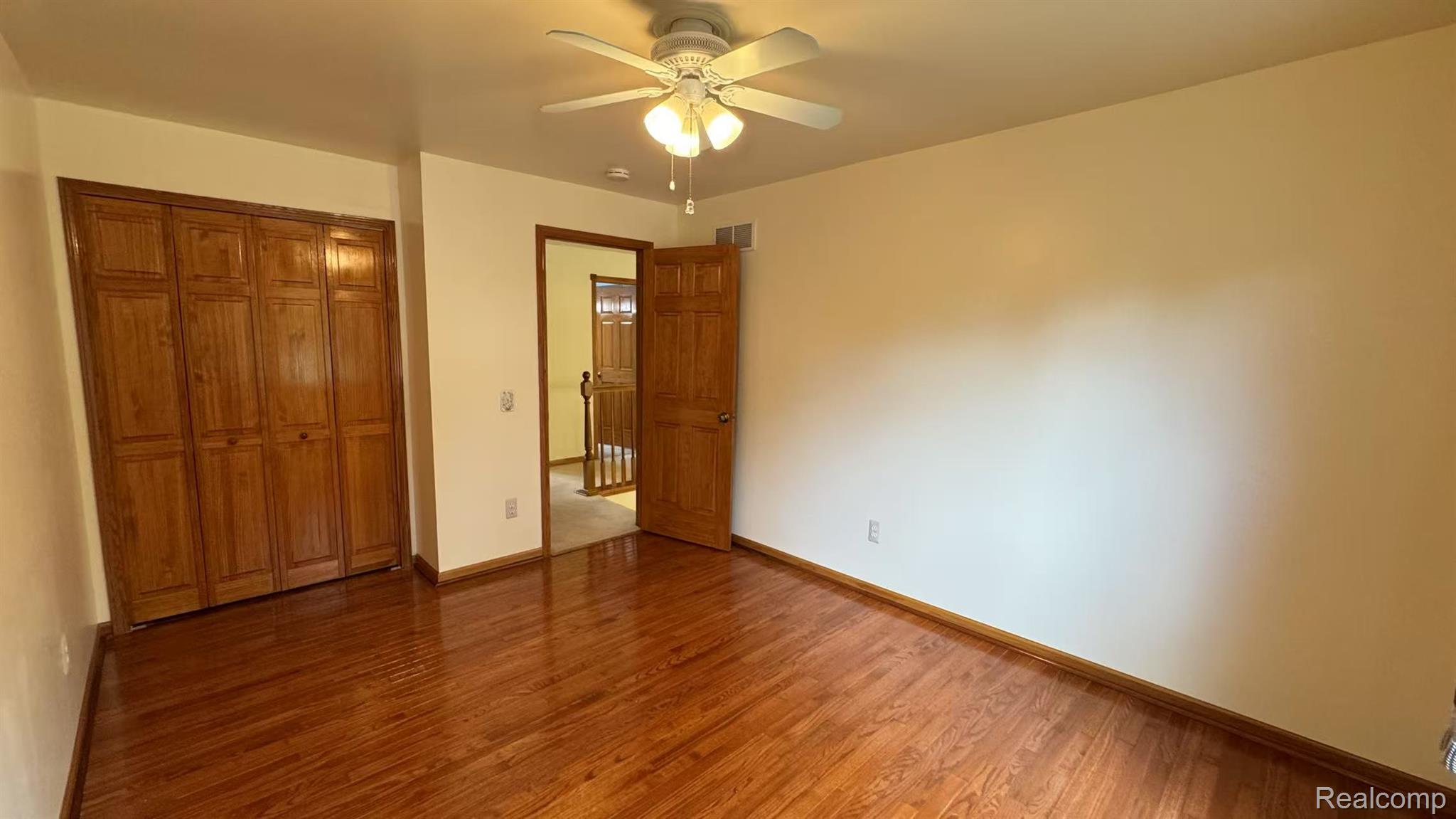 3440 Salem Drive Rochester, MI 48306 - Photo 22 of 33 Interior room featuring wood-finish flooring, a ceiling fan with integrated lighting, and a bi-fold closet with wood-panel doors