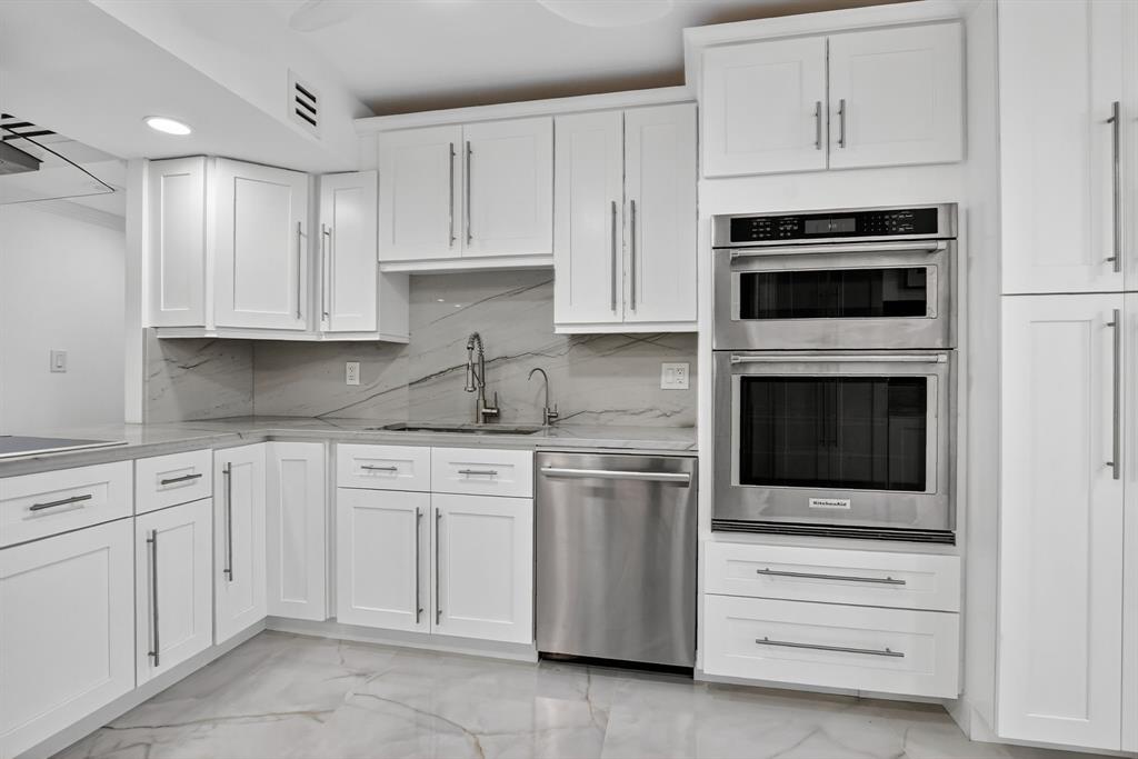 7145 Promenade Drive, Unit C702 Boca Raton, FL 33433 - Photo 27 of 82 a kitchen with white cabinets and stainless steel appliances