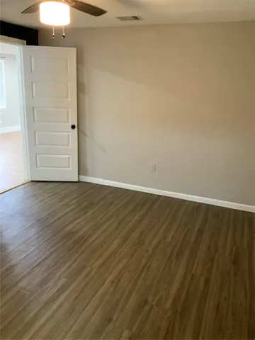 a view of an empty room with closet and wooden floor