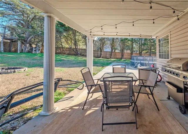 a view of a patio with table and chairs potted plants and floor to ceiling window