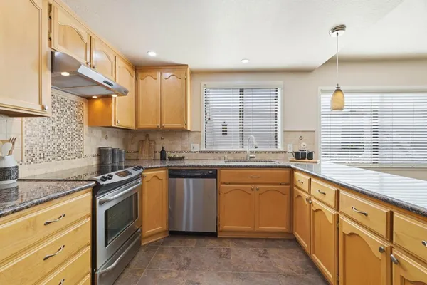 a kitchen with granite countertop sink stove and cabinets