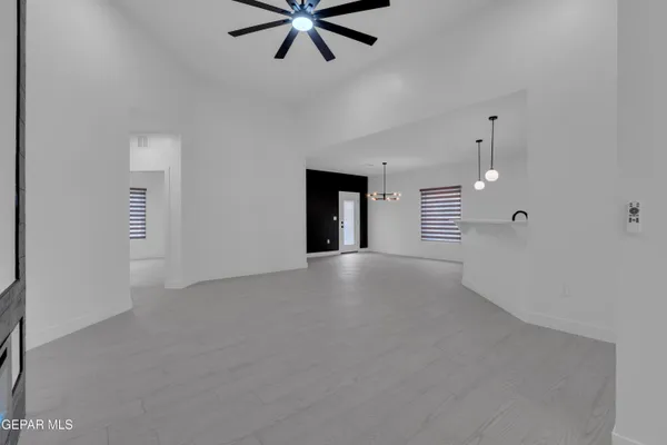 an empty room with ceiling fan and windows