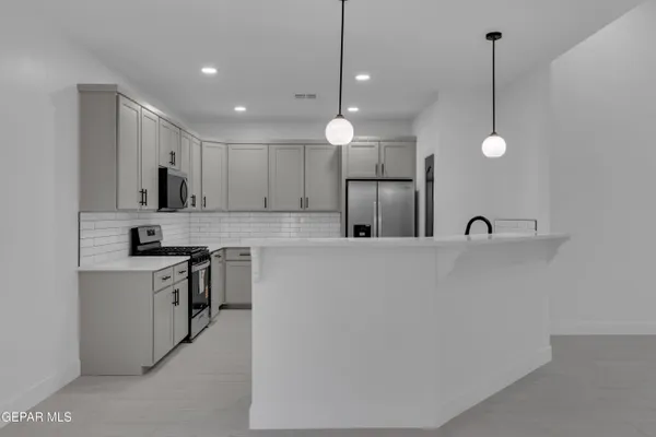 a kitchen with stainless steel appliances white cabinets a sink and a stove