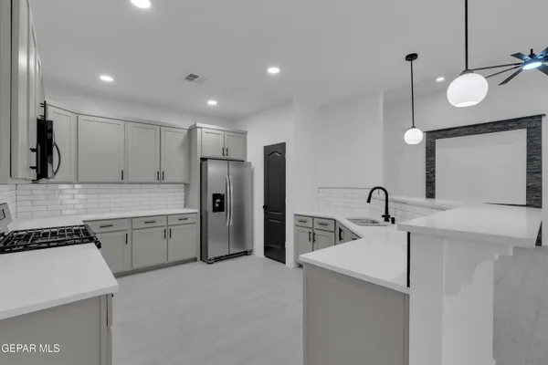 a kitchen with stainless steel appliances granite countertop a stove a sink and a microwave
