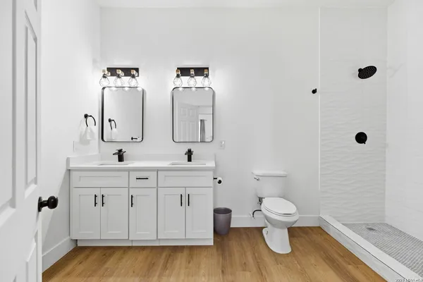 a bathroom with double vanity sink a mirror and a toilet