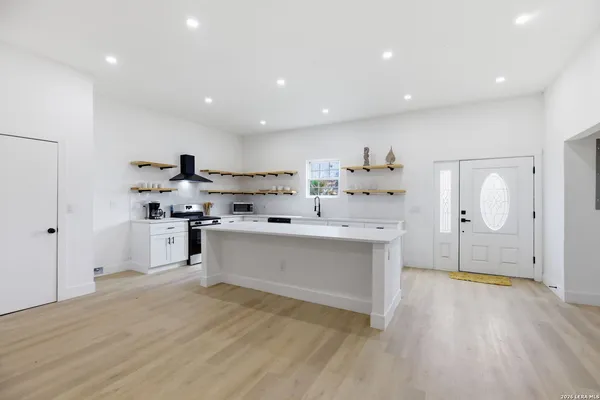 a large white kitchen with kitchen island a sink stainless steel appliances and cabinets