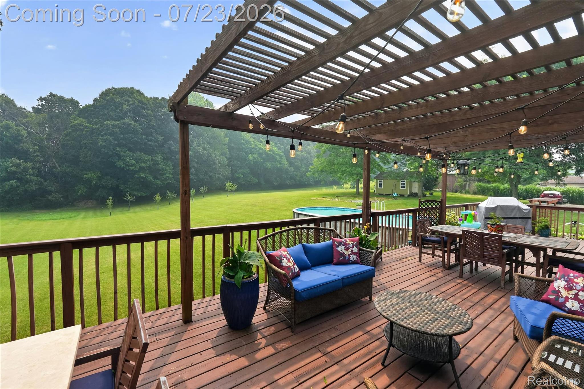 2795 Bird Road Ortonville, MI 48462 - Photo 53 of 62 Expansive wooden deck featuring a slatted pergola, string lighting, and a perimeter railing