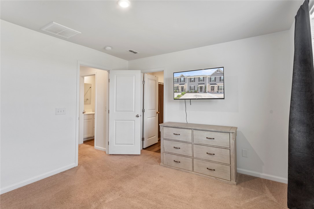137 Nicklaus Drive Anderson, SC 29621 - Photo 21 of 37 A well-lit bedroom features plush carpeting and convenient access to an adjoining bathroom.