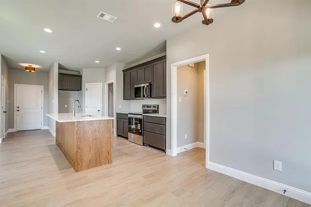 a view of kitchen with stainless steel appliances granite countertop a refrigerator a sink a stove and a wooden floors