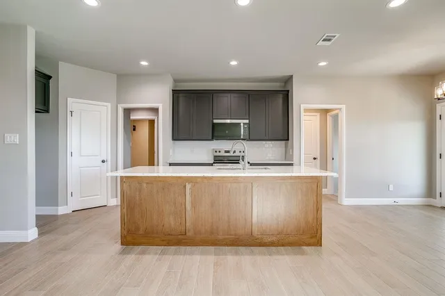 a large kitchen with wooden floor and a refrigerator