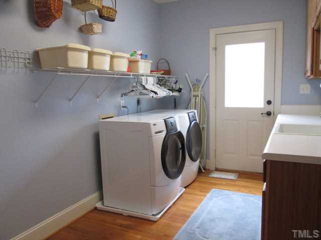 5305 Woodlaurel Court Raleigh, NC 27613 - Photo 19 of 25 First floor utility room features hardwood floors, cabinet with sink, door leads out to deck. The cabinet space is perfect for storing laundry detergent and cleaning supplies!