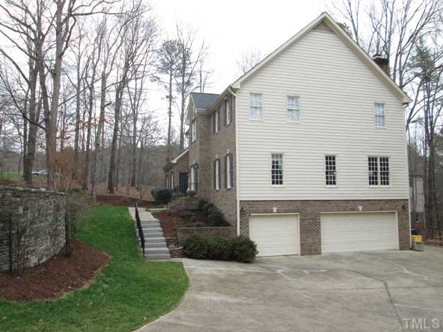 5305 Woodlaurel Court Raleigh, NC 27613 - Photo 3 of 25 Side view of your home with a 3 car garage and huge parking area, making for lots of parking space when you have guests over! THhre are lots of mature trees, so get outside and enjoy your nice private lot and all the lovely nature that surrounds you!