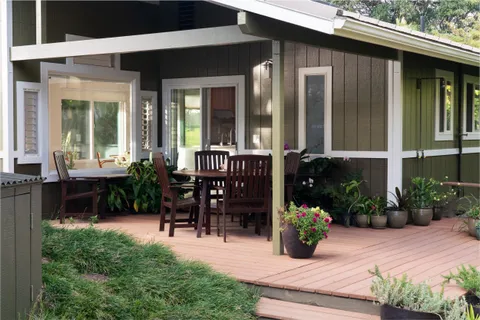 a view of a patio with table and chairs potted plants and floor to ceiling window