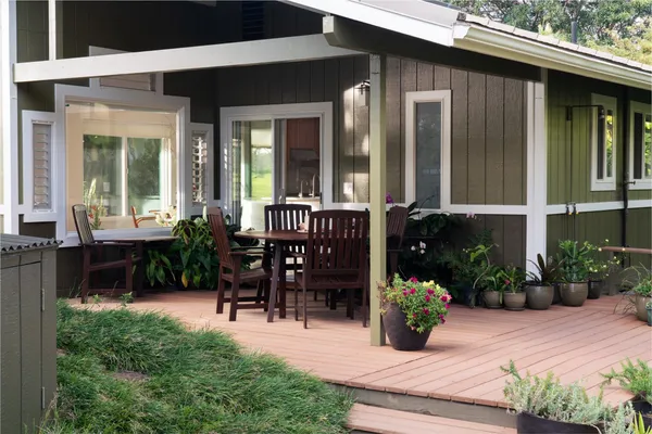 a view of a patio with table and chairs potted plants and floor to ceiling window